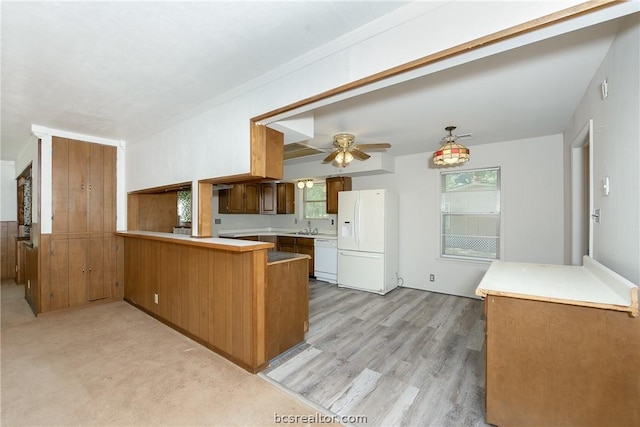 kitchen with kitchen peninsula, white appliances, light hardwood / wood-style flooring, and plenty of natural light