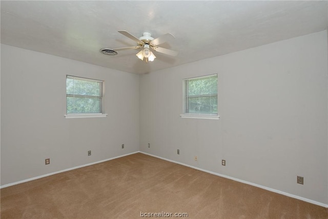 spare room featuring ceiling fan, light colored carpet, and a healthy amount of sunlight