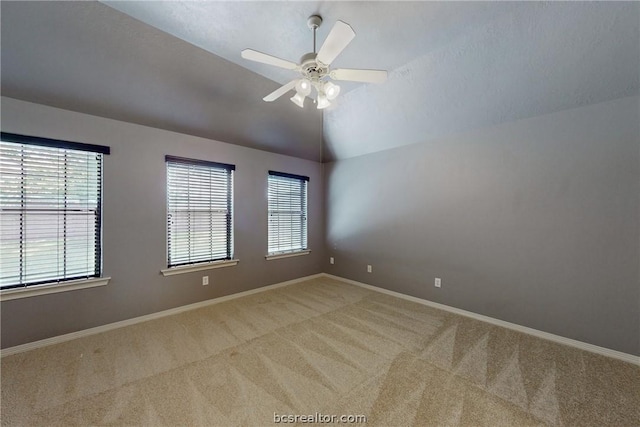 empty room with ceiling fan, light colored carpet, and vaulted ceiling