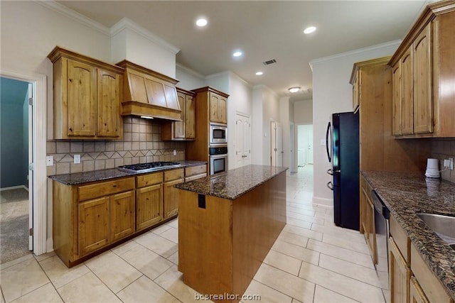 kitchen with dark stone counters, ornamental molding, stainless steel appliances, a center island, and light tile patterned flooring