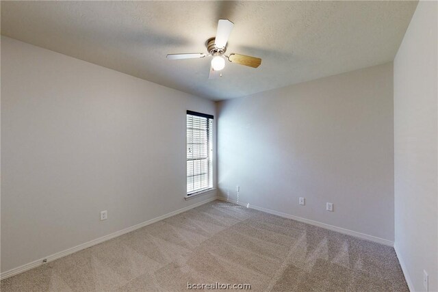 spare room featuring ceiling fan, light colored carpet, and a textured ceiling