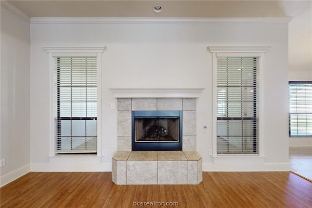 details featuring a tile fireplace, wood-type flooring, and crown molding