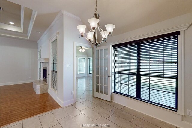 unfurnished dining area with ceiling fan with notable chandelier, light wood-type flooring, and ornamental molding