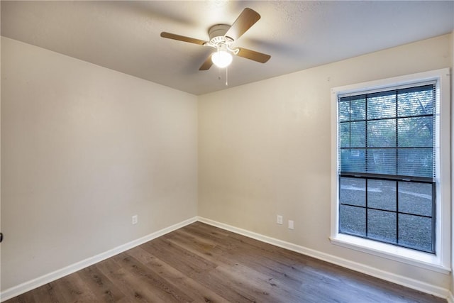 empty room with a wealth of natural light, ceiling fan, and hardwood / wood-style flooring