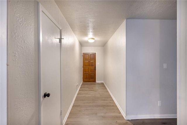 hallway featuring light wood-type flooring and a textured ceiling