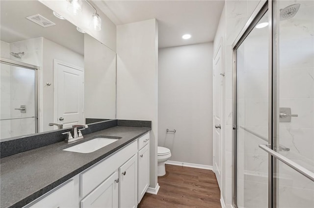 bathroom with toilet, vanity, a shower with door, and hardwood / wood-style flooring