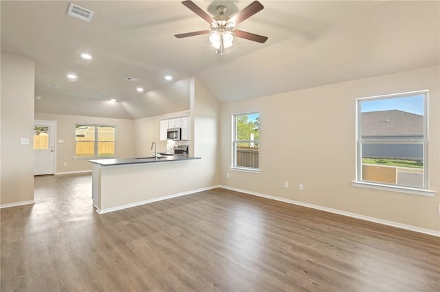 kitchen featuring kitchen peninsula, white cabinetry, lofted ceiling, and a wealth of natural light