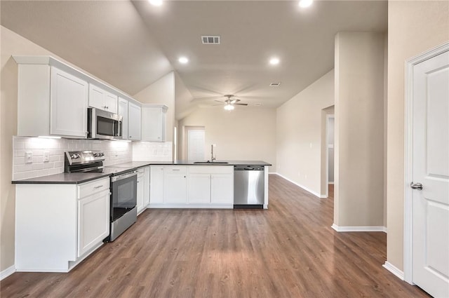 kitchen with appliances with stainless steel finishes, sink, hardwood / wood-style flooring, white cabinetry, and lofted ceiling