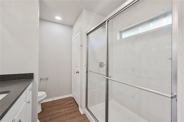 bathroom featuring vanity, hardwood / wood-style flooring, toilet, and a shower with door