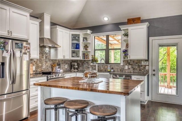 kitchen with open shelves, a sink, butcher block countertops, wall chimney exhaust hood, and stainless steel appliances