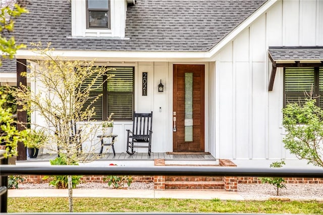 entrance to property featuring board and batten siding, roof with shingles, and covered porch