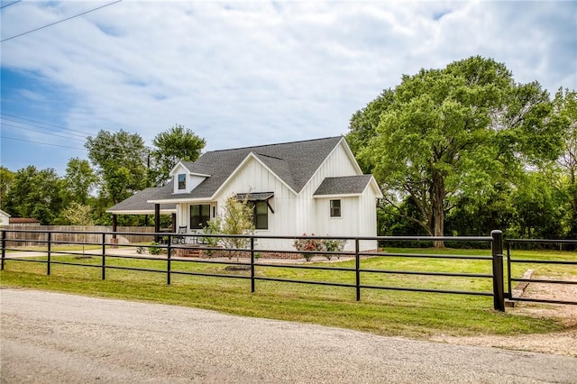 modern farmhouse style home with a shingled roof, a front lawn, board and batten siding, and fence