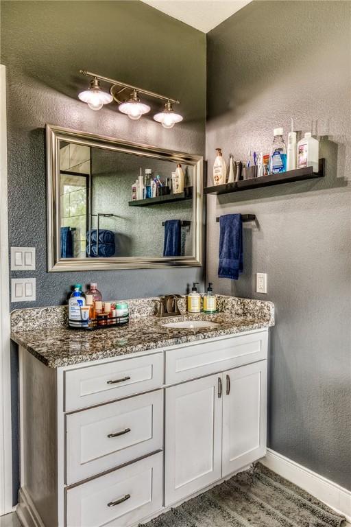 bathroom with a textured wall, baseboards, and vanity