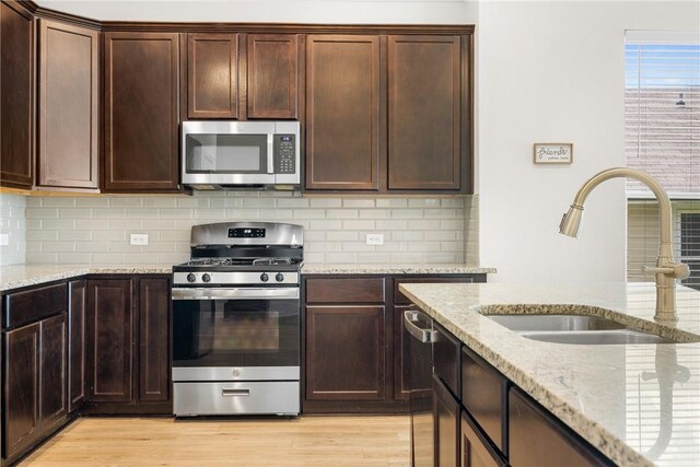 219 Cross Ln, Caldwell, TX 77836 - kitchen with stainless steel appliances, tasteful backsplash, light stone counters, and light wood-style floors