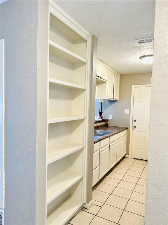 kitchen featuring light tile patterned flooring, white cabinetry, and a textured ceiling