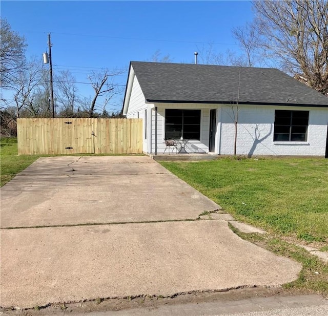 view of front of house with a front yard, fence, and roof with shingles