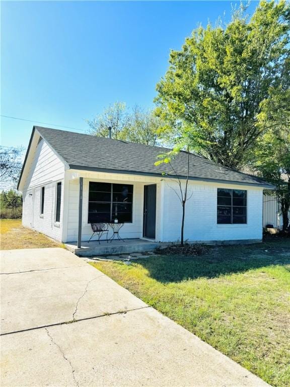 ranch-style house featuring covered porch and a front lawn