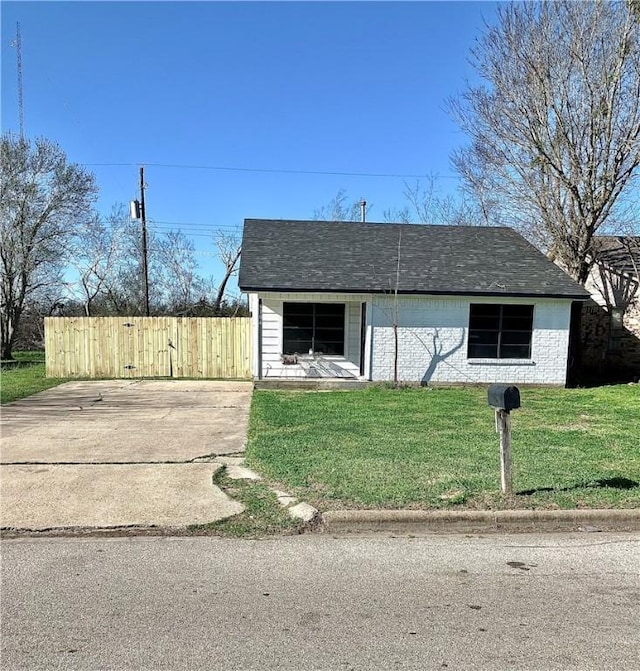 view of front facade featuring a front yard, fence, and brick siding