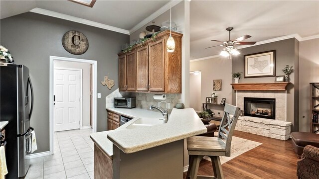 kitchen featuring a sink, stainless steel fridge with ice dispenser, light countertops, a peninsula, and a ceiling fan
