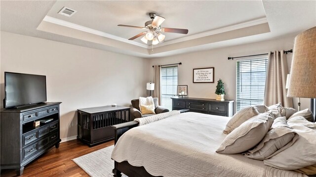 bedroom with a raised ceiling, visible vents, ornamental molding, and dark wood-type flooring