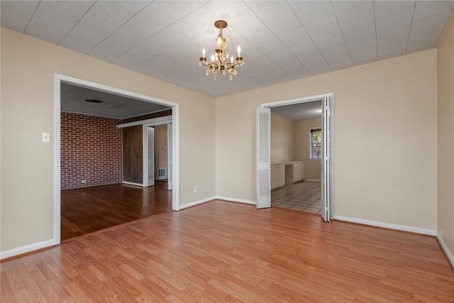 empty room featuring light hardwood / wood-style floors and a notable chandelier