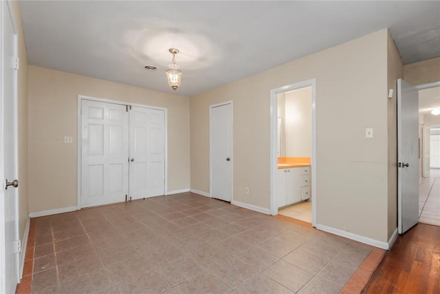 unfurnished bedroom with ensuite bath, a closet, and light tile patterned floors