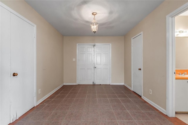 unfurnished bedroom with tile patterned floors, ensuite bathroom, and sink