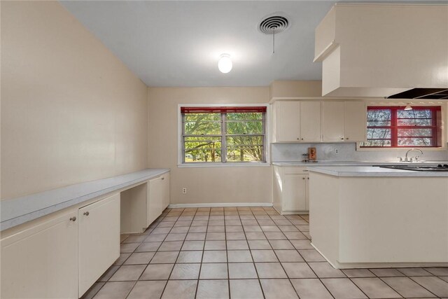 kitchen with white cabinets, backsplash, and light tile patterned flooring