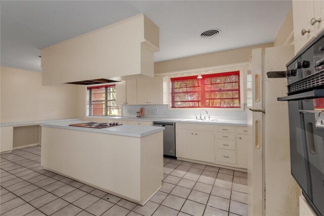 kitchen with light tile patterned flooring, a kitchen island, sink, and appliances with stainless steel finishes