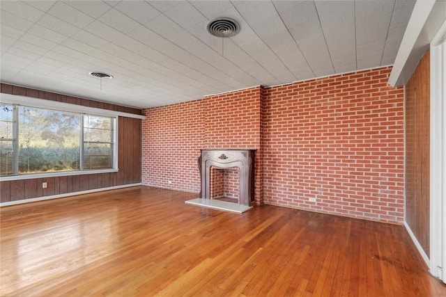 unfurnished living room with wood-type flooring and brick wall