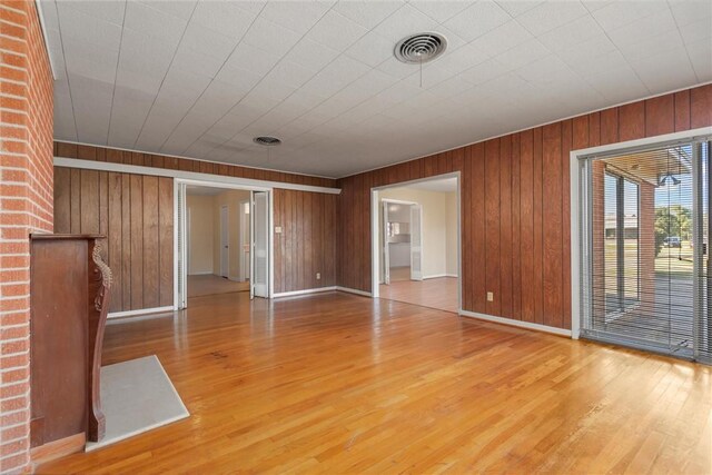 unfurnished room with light hardwood / wood-style flooring and wood walls