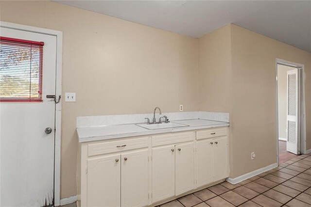 kitchen with white cabinets, light tile patterned floors, and sink