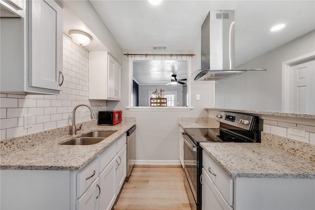 kitchen featuring island range hood, a sink, visible vents, appliances with stainless steel finishes, and backsplash