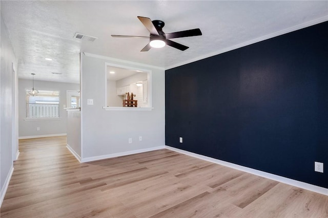 unfurnished room featuring crown molding, visible vents, a ceiling fan, wood finished floors, and baseboards