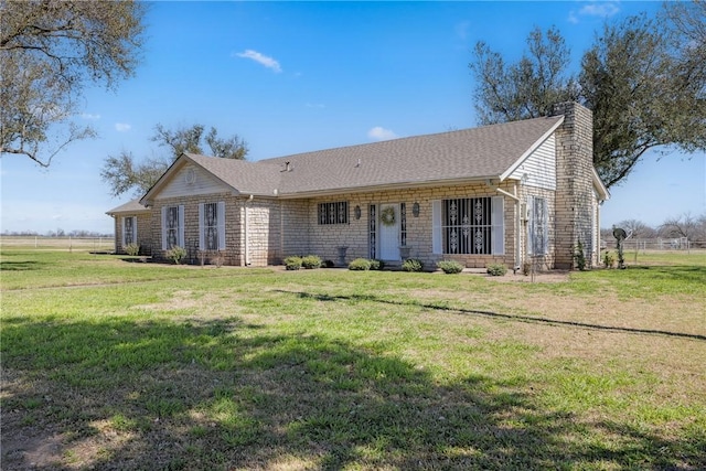 ranch-style home featuring a shingled roof, a front yard, and a chimney