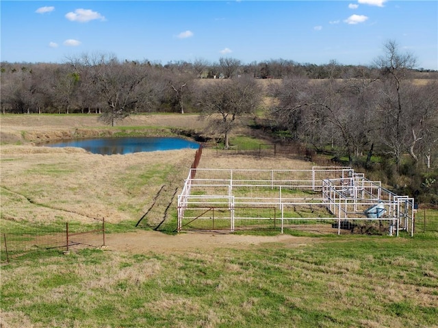 exterior space featuring a rural view, a lawn, fence, and a water view