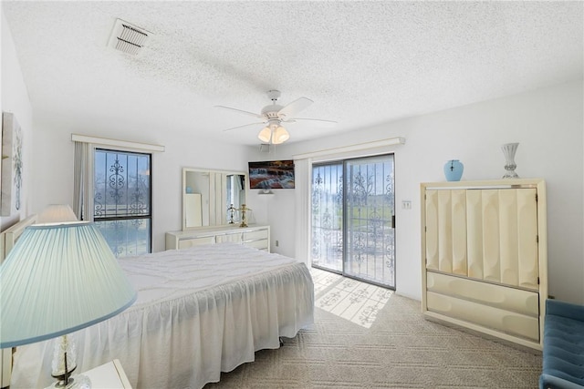 bedroom with access to exterior, visible vents, ceiling fan, carpet, and a textured ceiling