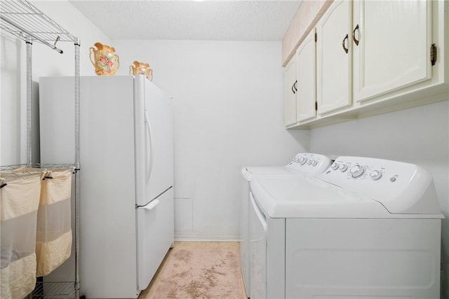 washroom featuring washing machine and dryer, cabinet space, and a textured ceiling