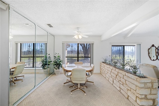 unfurnished dining area featuring carpet flooring, a ceiling fan, visible vents, and a textured ceiling