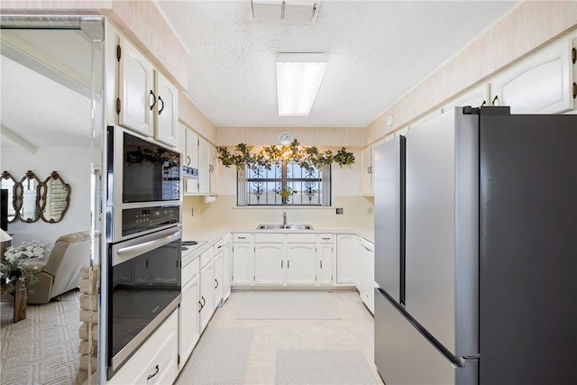 kitchen with a sink, visible vents, white cabinetry, and stainless steel appliances