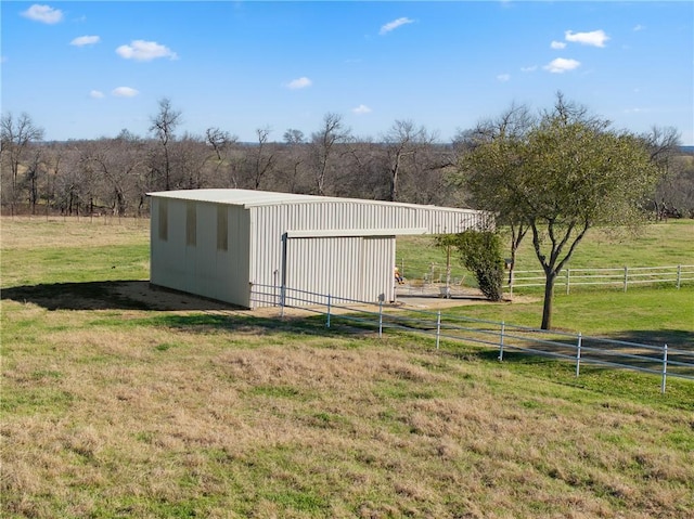 view of pole building with a rural view, a yard, and fence