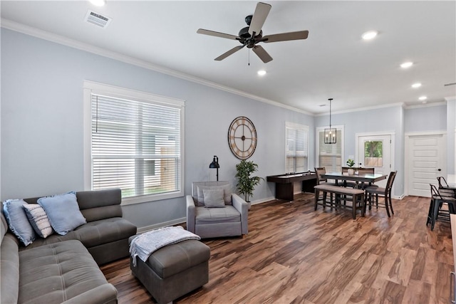 living room featuring visible vents, crown molding, wood finished floors, baseboards, and ceiling fan with notable chandelier
