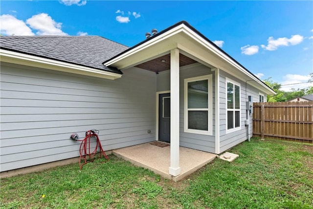 rear view of property with a lawn, a patio, fence, and roof with shingles