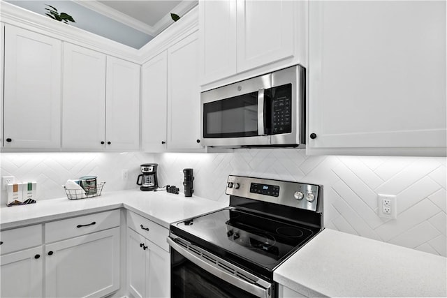 kitchen with white cabinetry, appliances with stainless steel finishes, decorative backsplash, and ornamental molding