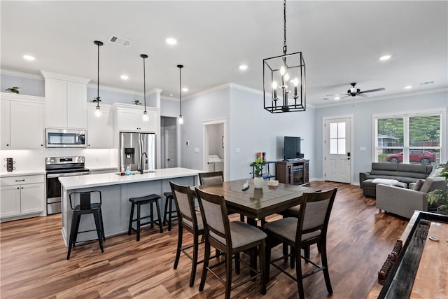 dining area featuring ceiling fan with notable chandelier, recessed lighting, wood finished floors, visible vents, and ornamental molding