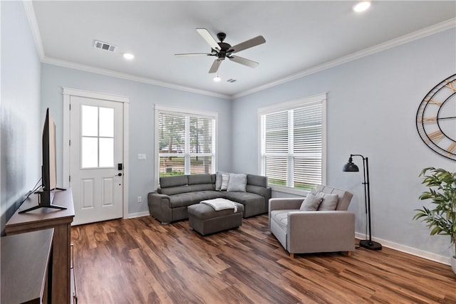 living room featuring ceiling fan, baseboards, wood finished floors, visible vents, and ornamental molding