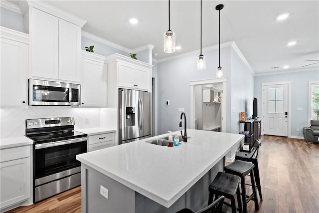 kitchen with a sink, ornamental molding, stainless steel appliances, and recessed lighting