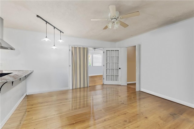 unfurnished living room featuring ceiling fan, a textured ceiling, and light wood-type flooring