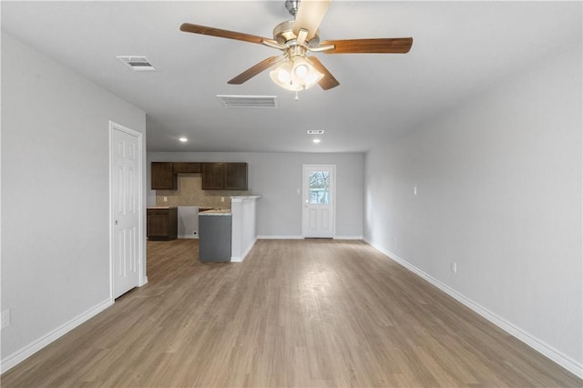 unfurnished living room with a ceiling fan, visible vents, baseboards, and wood finished floors