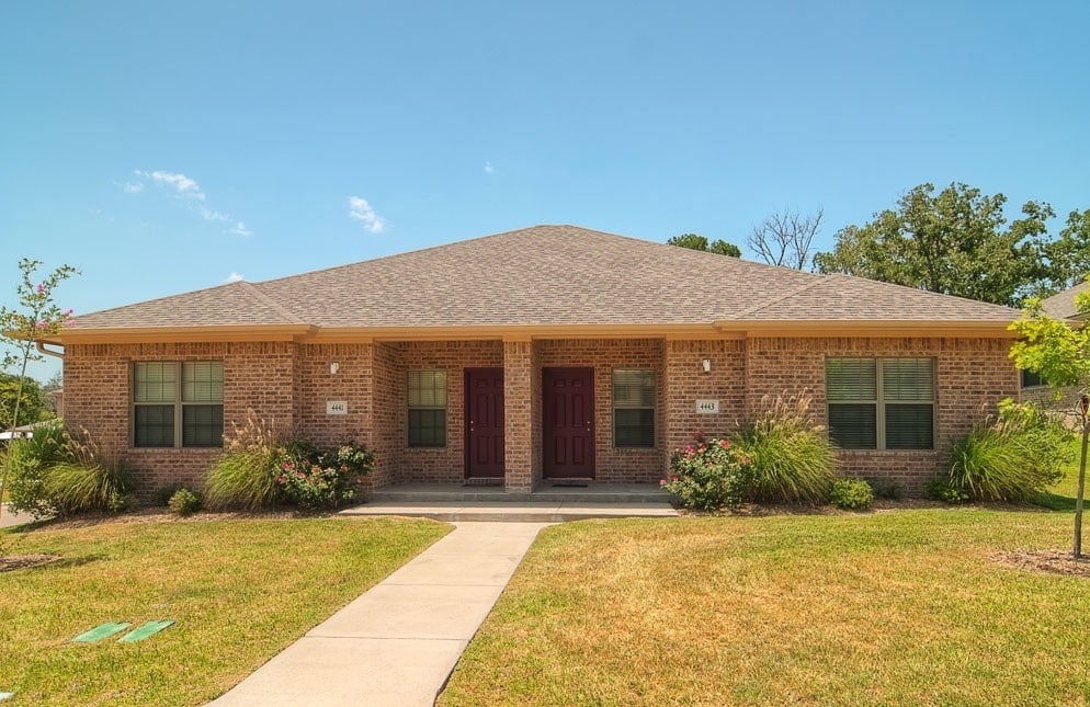 ranch-style house featuring covered porch and a front yard